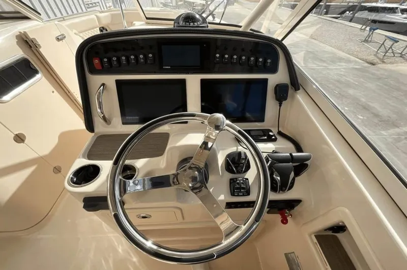 Slide: The Image of 2022 Grady-White Freedom 307 boat dashboard with steering wheel and control panels. - 51