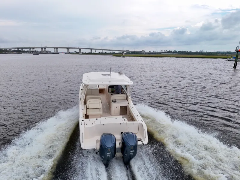 Slide: The Image of 2022 Grady-White Freedom 307 boat cruising on a river with a bridge in the background. - 7