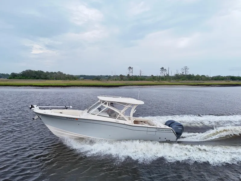 Slide: The Image of 2022 Grady-White Freedom 307 boat cruising on a calm river under a cloudy sky. - 8