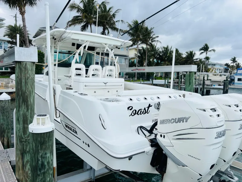 Slide: The Image of 2016 Boston Whaler 370 Outrage docked, featuring triple Mercury engines, surrounded by palm trees. - 3