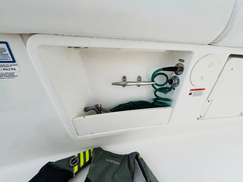 Slide: The Image of Boston Whaler 370 Outrage 2016 boat compartment with coiled hose and life jacket. - 38