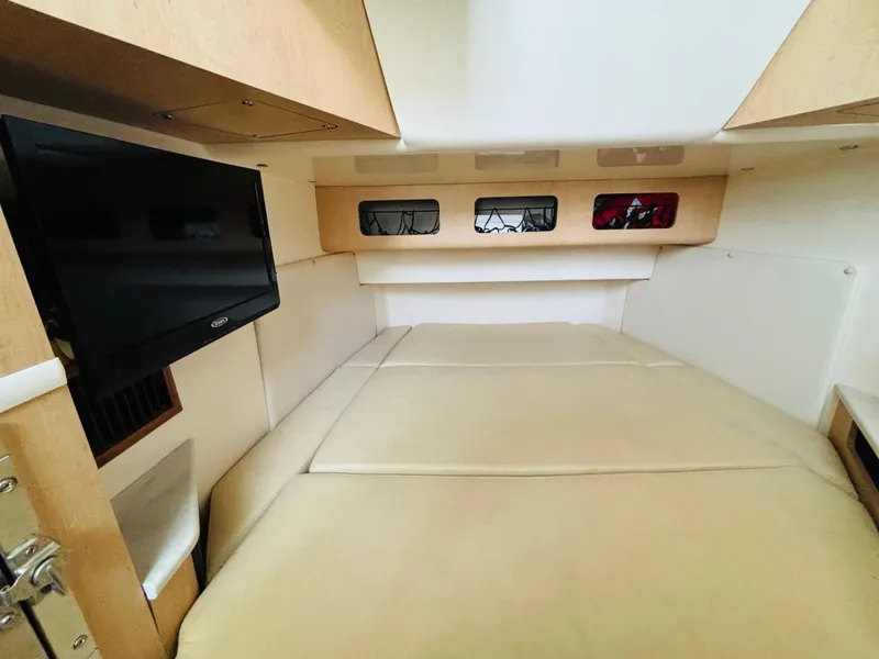 Slide: The Image of 2016 Boston Whaler 370 Outrage cabin interior with bed and wall-mounted TV. - 42