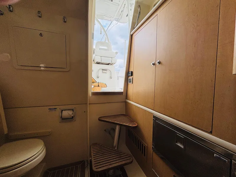 Slide: The Image of 2016 Boston Whaler 370 Outrage cabin interior with wooden cabinetry and seating. - 48