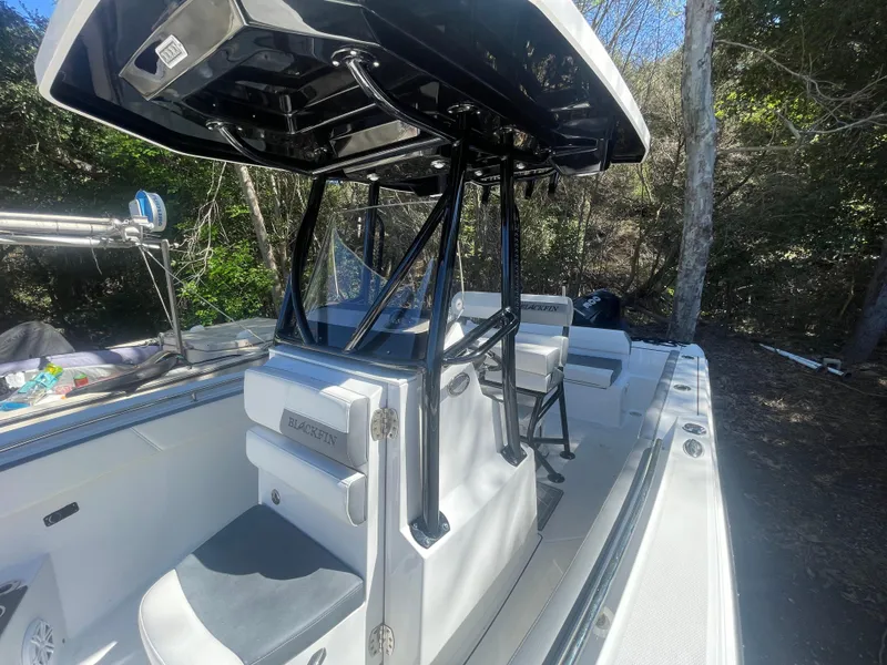 Slide: The Image of 2019 Blackfin 212 CC boat interior with seating and console, surrounded by trees. - 11