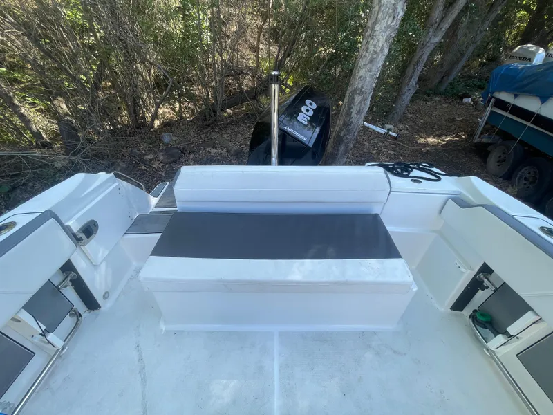 Slide: The Image of 2019 Blackfin 212 CC boat interior with seating and storage, surrounded by trees. - 4