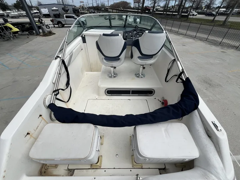 Slide: The Image of 1992 Sea Ray 230 Sundancer boat interior with dual captain chairs and storage compartments. - 12