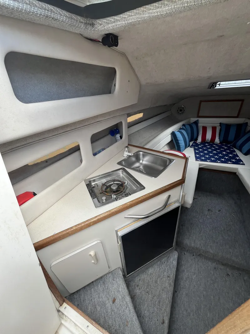 Slide: The Image of Interior of 1992 Sea Ray 230 Sundancer with kitchenette and seating area. - 14