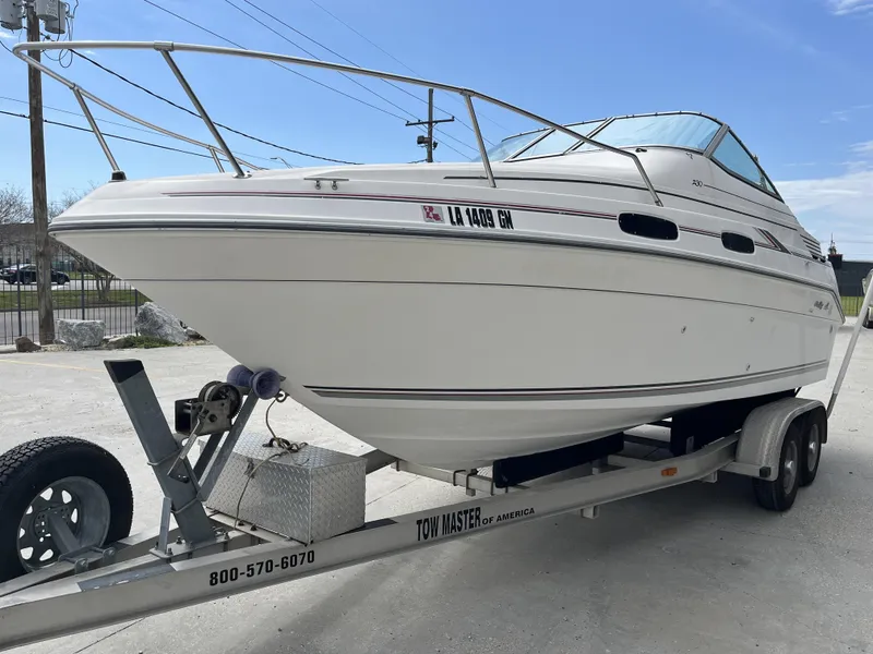 Slide: The Image of 1992 Sea Ray 230 Sundancer boat on trailer, parked outdoors under clear sky. - 3