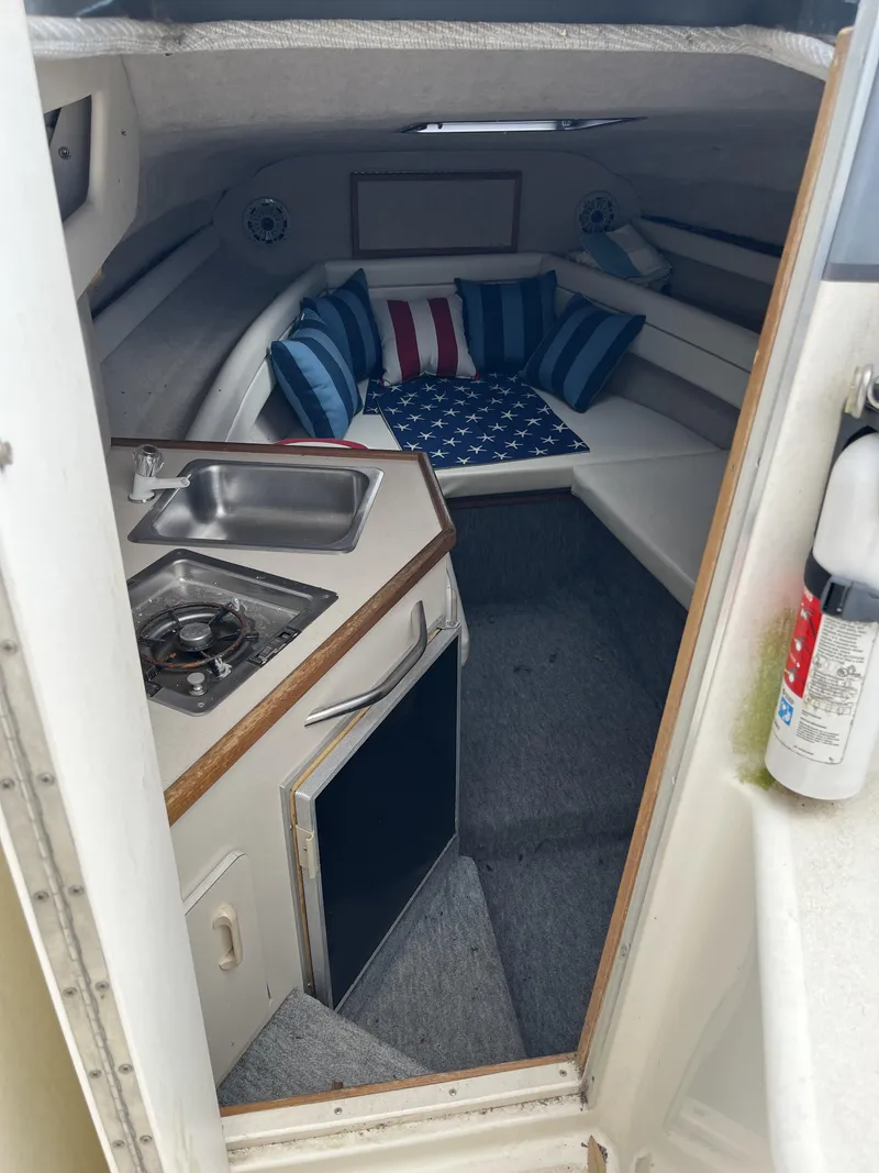 Slide: The Image of Interior of a 1992 Sea Ray 230 Sundancer boat with kitchenette and seating area. - 8