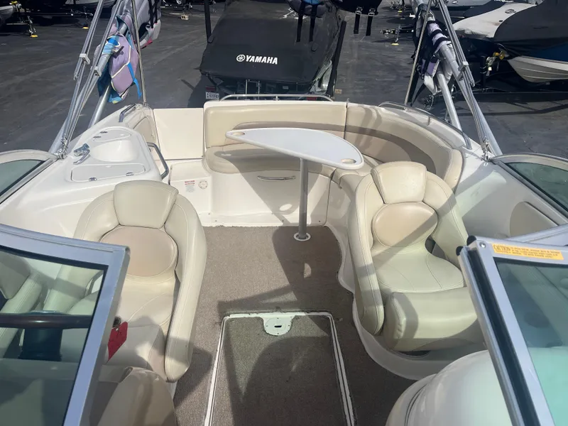 Slide: The Image of 2004 Chaparral Sunesta 254 boat interior with seating and table, parked in a marina. - 10