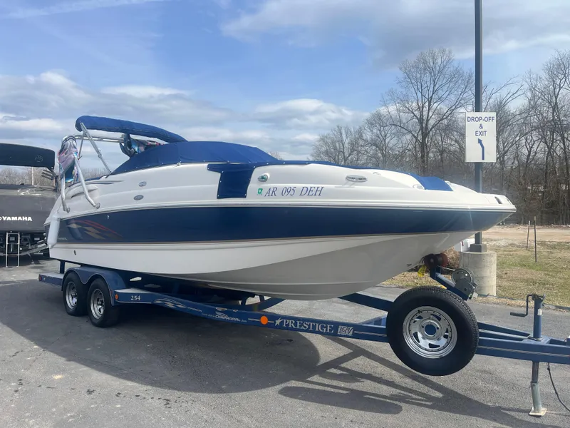 Slide: The Image of 2004 Chaparral Sunesta 254 boat on trailer, parked outdoors under cloudy sky. - 6