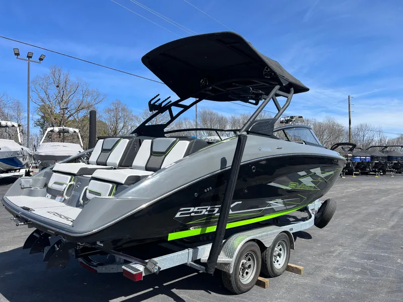 Slide: The Image of 2021 Yamaha Boats 255X on trailer, sleek design, black and green accents, outdoor display. - 3