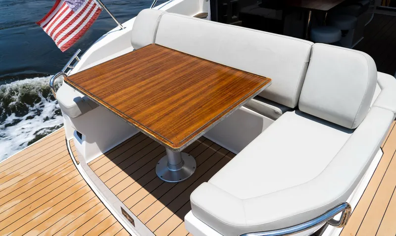 Slide: The Image of Luxury seating area on 2022 Bavaria SR41 yacht with wooden table and American flag. - 17