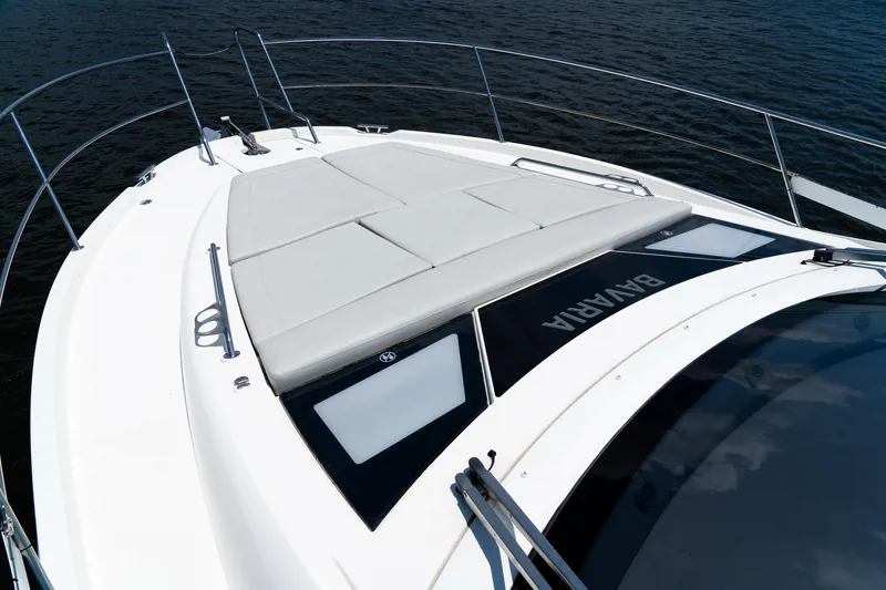 Slide: The Image of 2022 Bavaria SR41 yacht deck with sunbathing area, sleek design, and railing on calm water. - 6