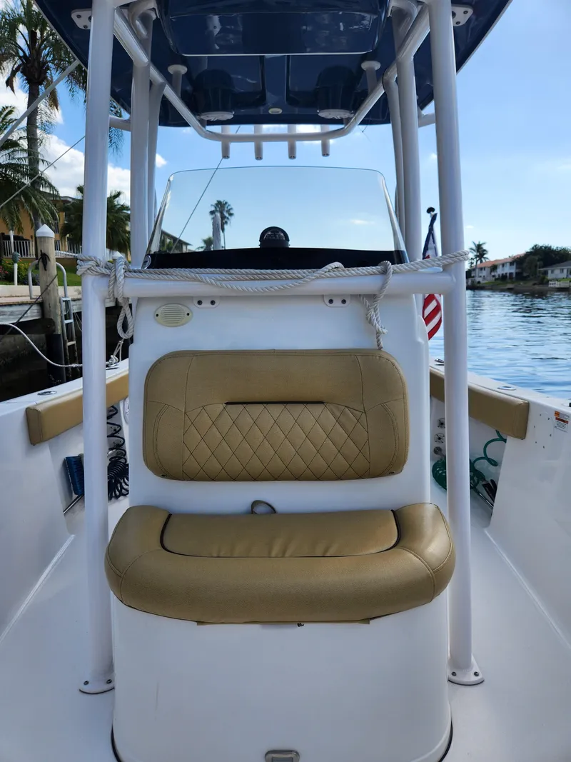 Slide: The Image of 2023 Sportsman Heritage 211 Center Console boat with tan seating, docked by a waterfront. - 22