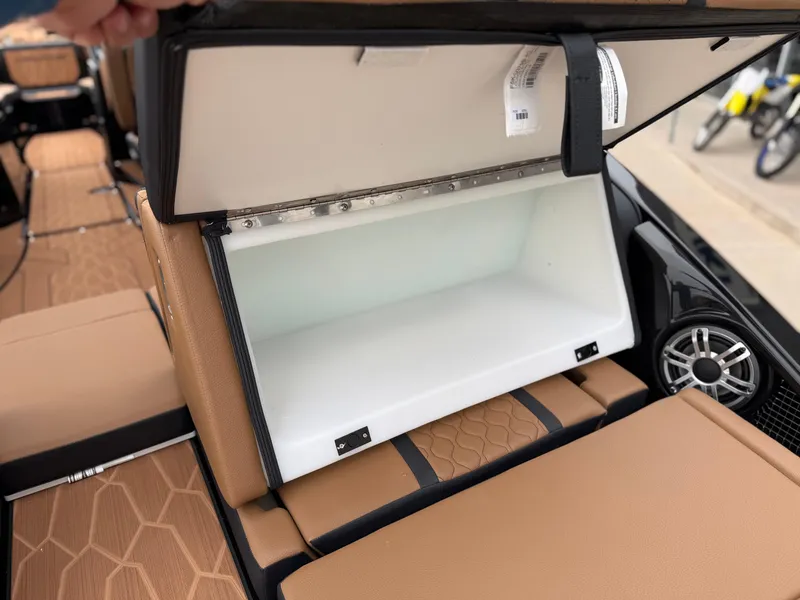 Slide: The Image of 2025 Yamaha Boats 255XD storage compartment with tan seating and speaker detail. - 22