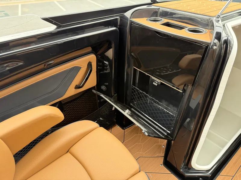 Slide: The Image of 2025 Yamaha Boats 255XD interior with tan seating and sleek black storage compartment. - 29