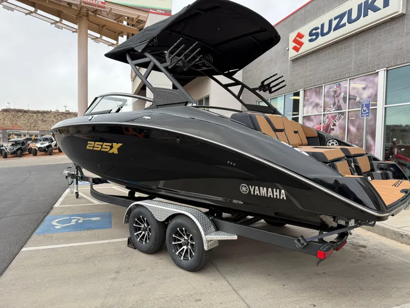 Slide: The Image of 2025 Yamaha Boats 255XD in black on trailer, parked outside Suzuki dealership. - 3