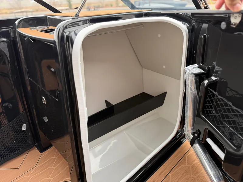 Slide: The Image of 2025 Yamaha Boats 255XD storage compartment with sleek black and white interior design. - 58