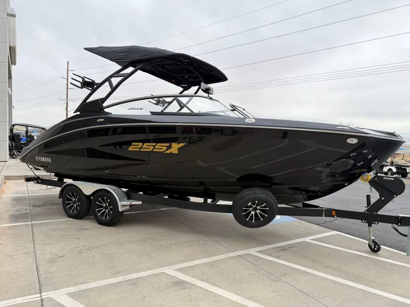 Slide: The Image of 2025 Yamaha Boats 255XD, sleek black design on a trailer, parked outdoors. - 9