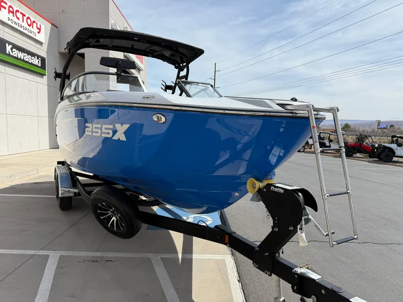 Slide: The Image of 2025 Yamaha Boats 255XD in blue on trailer, parked outside dealership. - 13