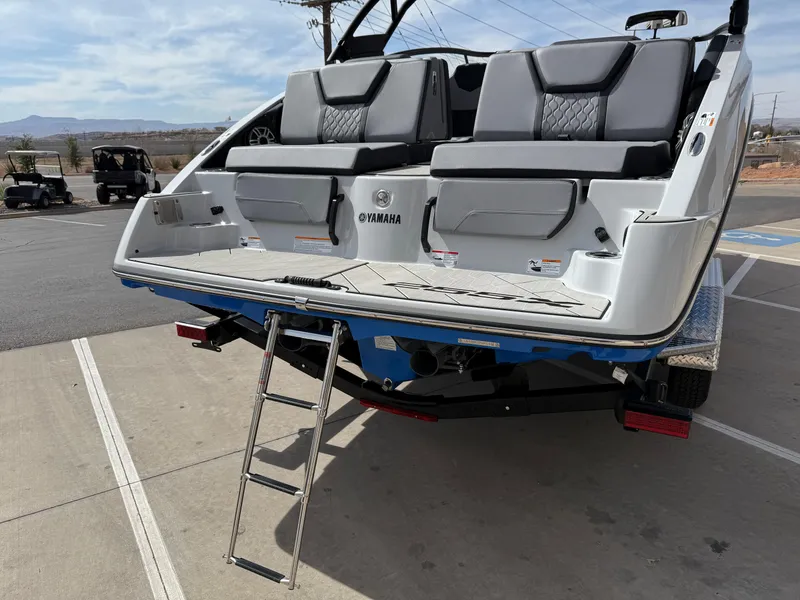 Slide: The Image of 2025 Yamaha Boats 255XD with rear seating and ladder, parked on a trailer. - 16