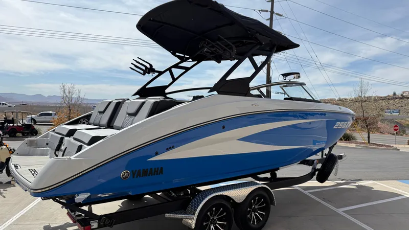 Slide: The Image of 2025 Yamaha Boats 255XD in blue and white on a trailer, parked outdoors. - 3