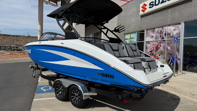 Slide: The Image of 2025 Yamaha Boats 255XD in blue and white on a trailer outside a dealership. - 7