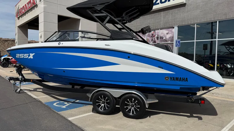 Slide: The Image of 2025 Yamaha Boats 255XD in blue and white, parked on a trailer outside a dealership. - 8