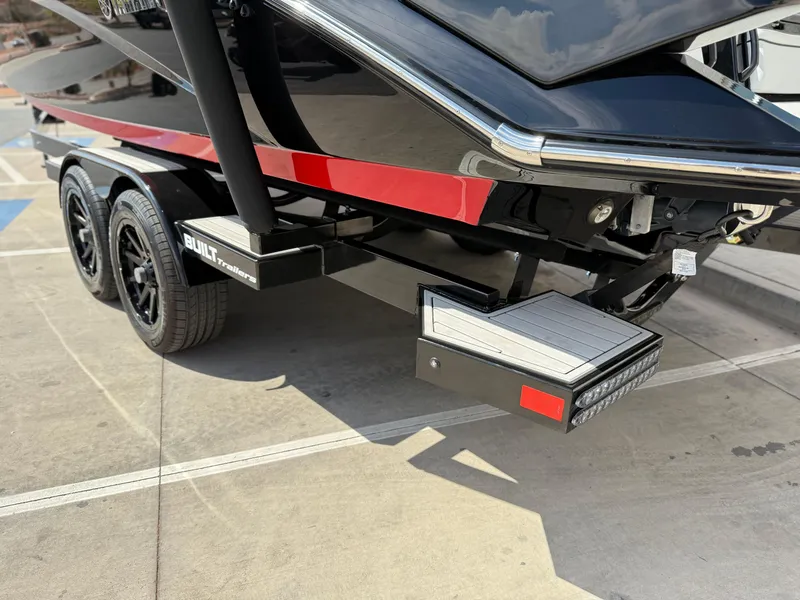 Slide: The Image of 2025 Yamaha Boats 275 SD trailer with dual axles and sleek black design. - 18