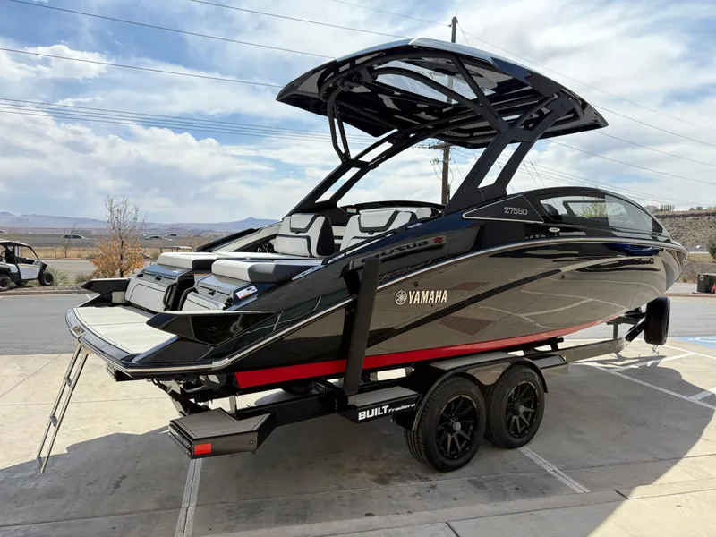 Slide: The Image of 2025 Yamaha Boats 275 SD on trailer, sleek design, black and red accents, outdoor setting. - 2