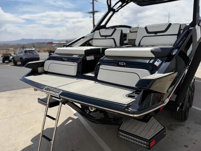 Slide: The Image of 2025 Yamaha Boats 275 SD with sleek seating and swim platform, parked outdoors. - 24