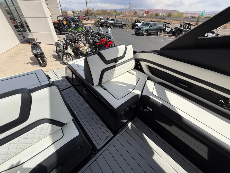 Slide: The Image of 2025 Yamaha Boats 275 SD interior with sleek seating and modern design, parked near motorcycles. - 43