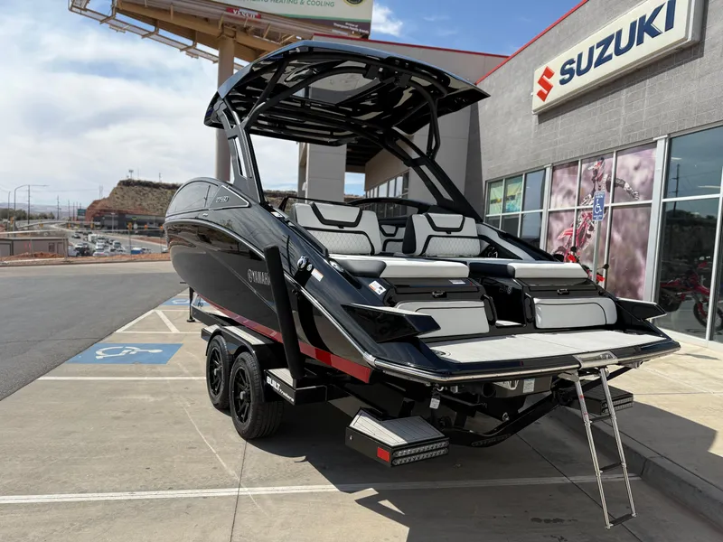 Slide: The Image of 2025 Yamaha Boats 275 SD, sleek black design, parked outside Suzuki dealership. - 5