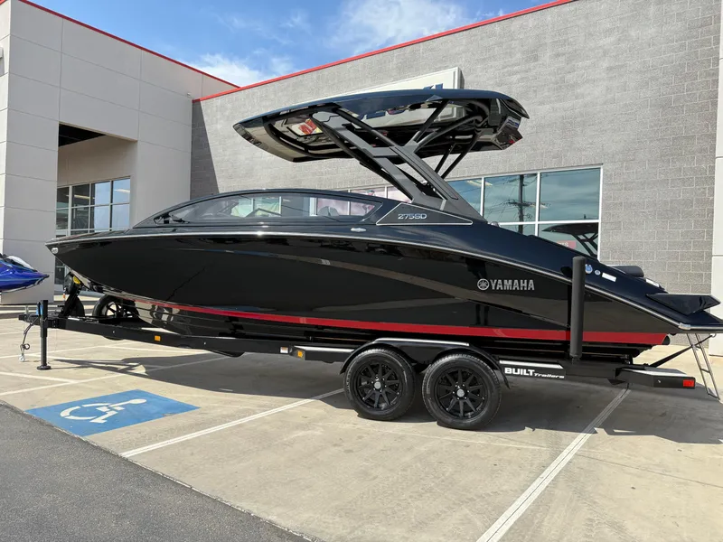 Slide: The Image of 2025 Yamaha Boats 275 SD in black, parked on a trailer outside a building. - 7