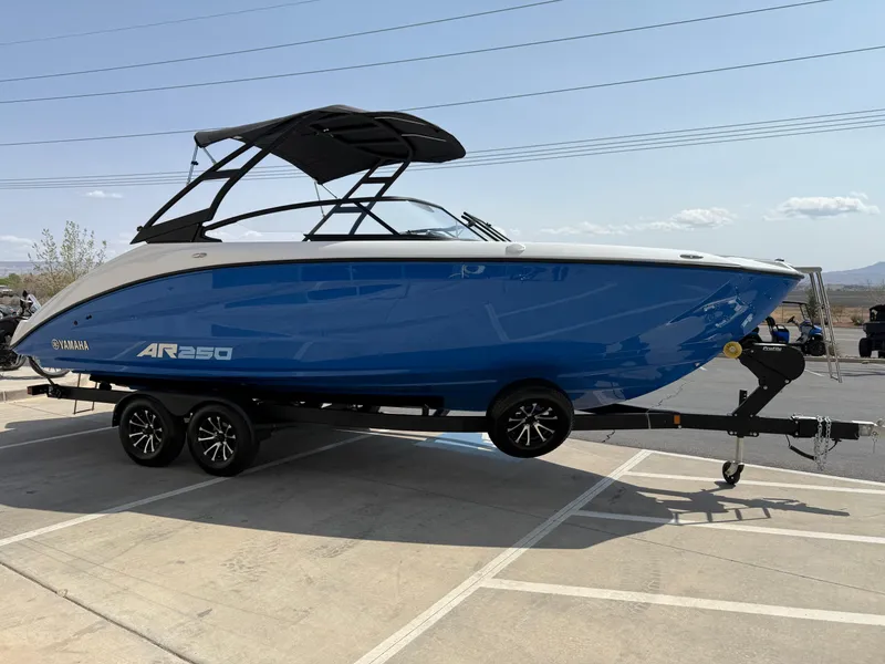 Slide: The Image of 2025 Yamaha AR250 boat in blue on a trailer, parked outdoors. - 11
