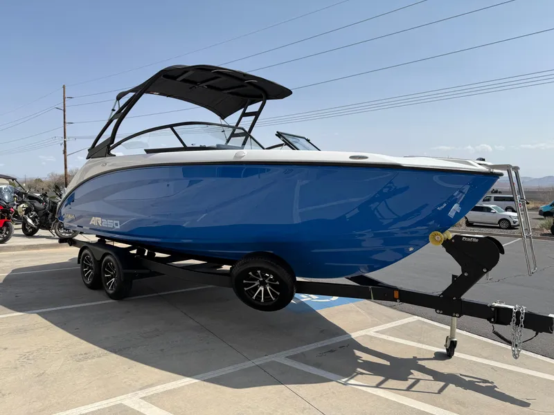 Slide: The Image of 2025 Yamaha Boats AR250 on trailer, blue hull, parked outdoors. - 12
