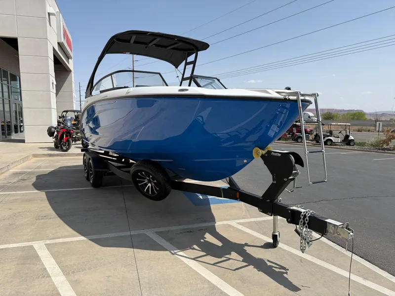 Slide: The Image of 2025 Yamaha Boats AR250 in blue on trailer, parked outside a building. - 13