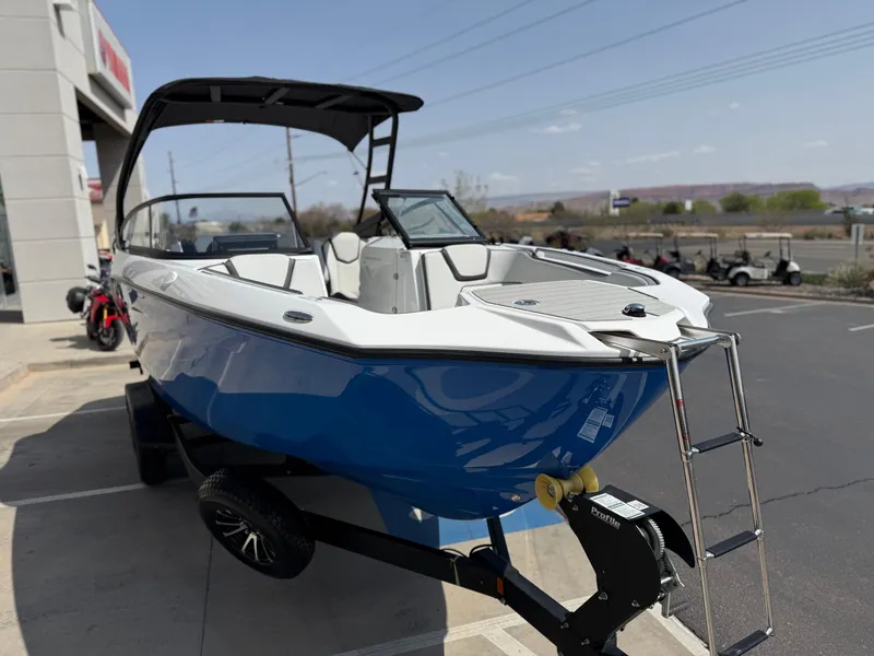 Slide: The Image of 2025 Yamaha Boats AR250, blue and white, parked on a trailer outside a dealership. - 18