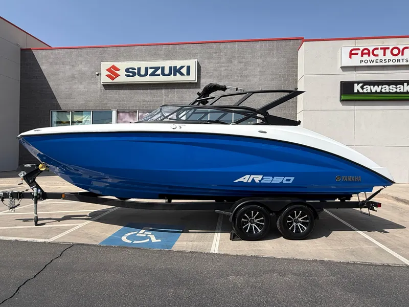 Slide: The Image of 2025 Yamaha AR250 boat in blue on a trailer outside a dealership. - 21