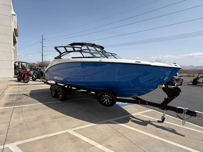 Slide: The Image of 2025 Yamaha Boats AR250 in blue, parked on a trailer in a lot. - 22