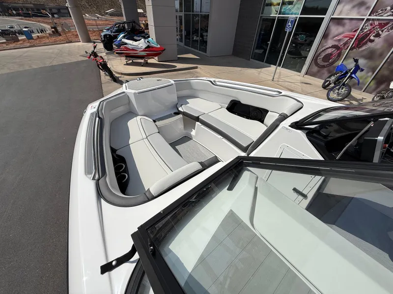 Slide: The Image of 2025 Yamaha Boats AR250 interior with white seating, parked outside a showroom. - 24