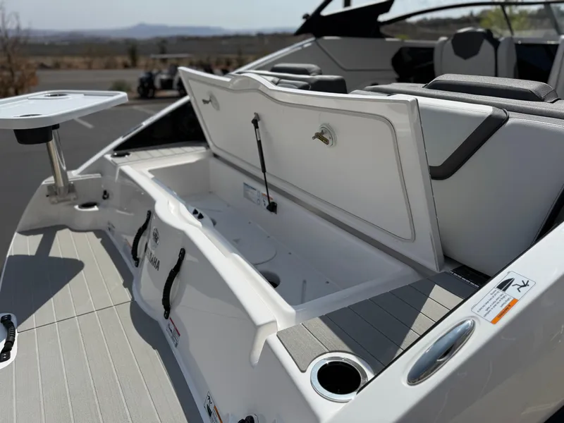 Slide: The Image of 2025 Yamaha Boats AR250 interior with open storage compartment and seating area. - 28