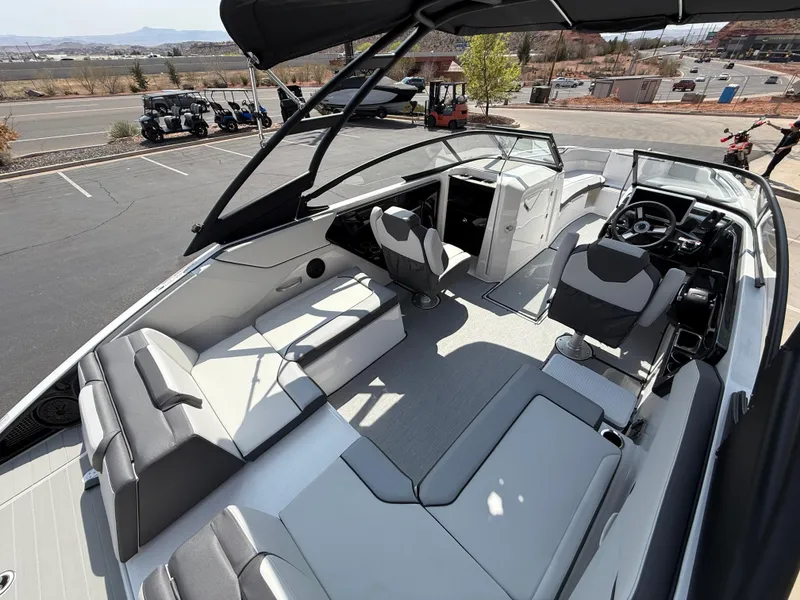 Slide: The Image of 2025 Yamaha Boats AR250 interior with modern seating and steering wheel, parked outdoors. - 36