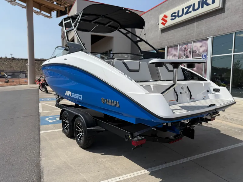 Slide: The Image of 2025 Yamaha AR250 boat in blue, parked outside a Suzuki dealership. - 5