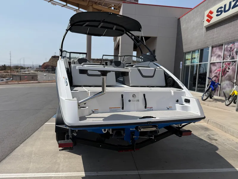 Slide: The Image of 2025 Yamaha Boats AR250 at dealership, rear view, showcasing sleek design and spacious seating. - 6