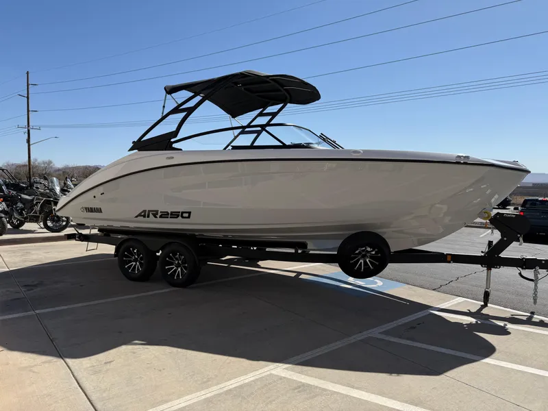 The Image of 2025 Yamaha Boats AR250 on trailer, parked outdoors under clear blue sky. - 1