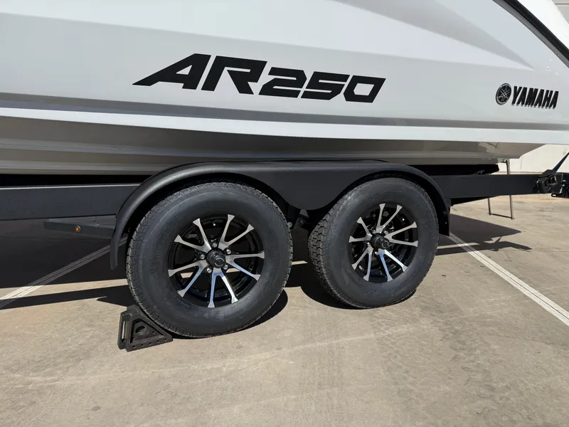 Slide: The Image of 2025 Yamaha Boats AR250 on trailer, showcasing sleek design and dual wheels. - 25