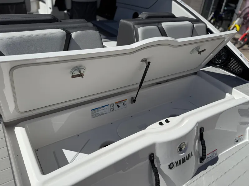 Slide: The Image of 2025 Yamaha Boats AR250 storage compartment with open lid, showcasing interior space. - 30