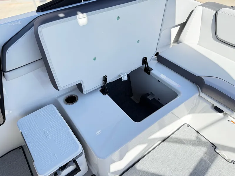 Slide: The Image of 2025 Yamaha Boats AR250 interior storage compartment with open lid and seating area. - 39